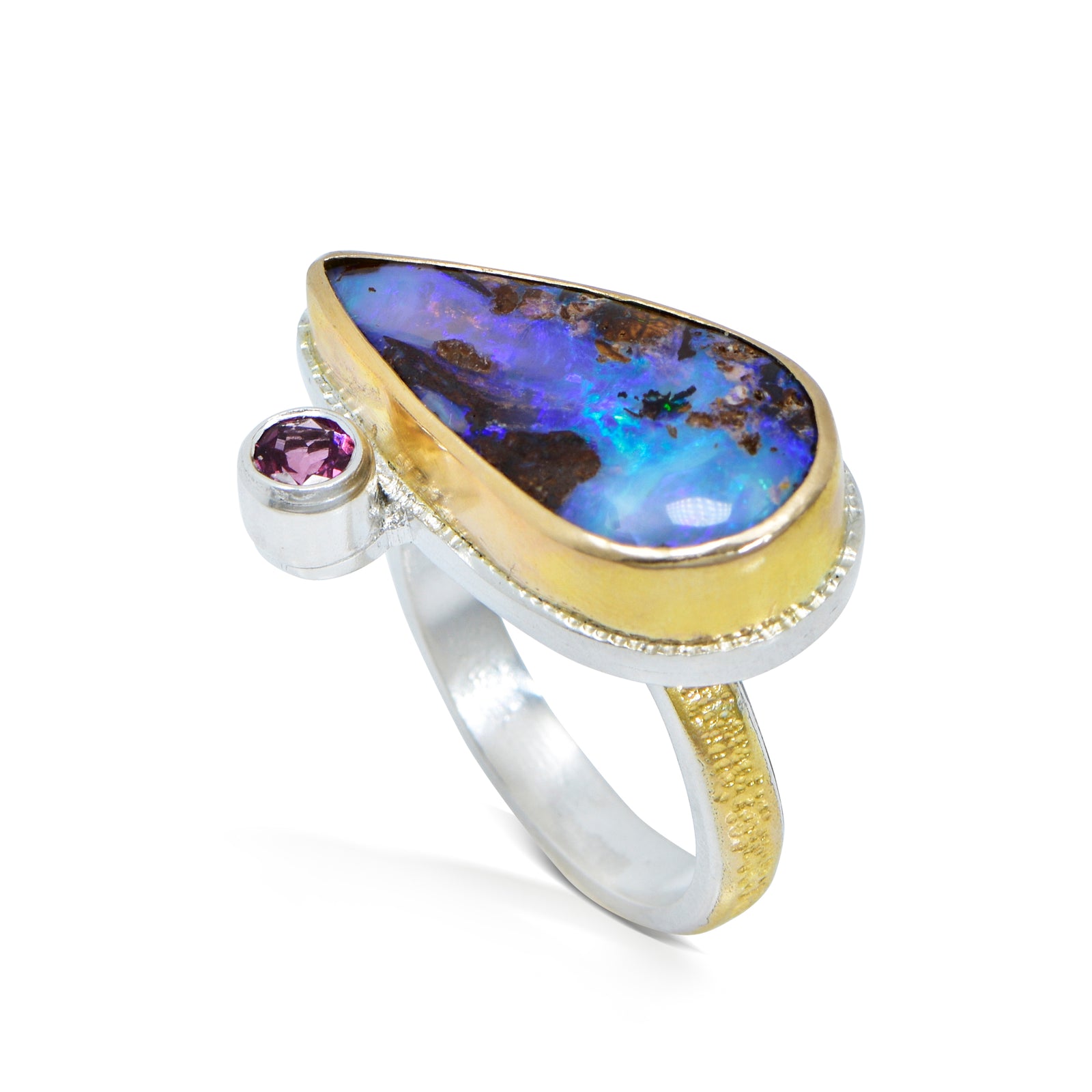 A boulder opal ring with an 18k bezel and a rhodolite garnet accent, set on an argentium silver band with 22kt overlay